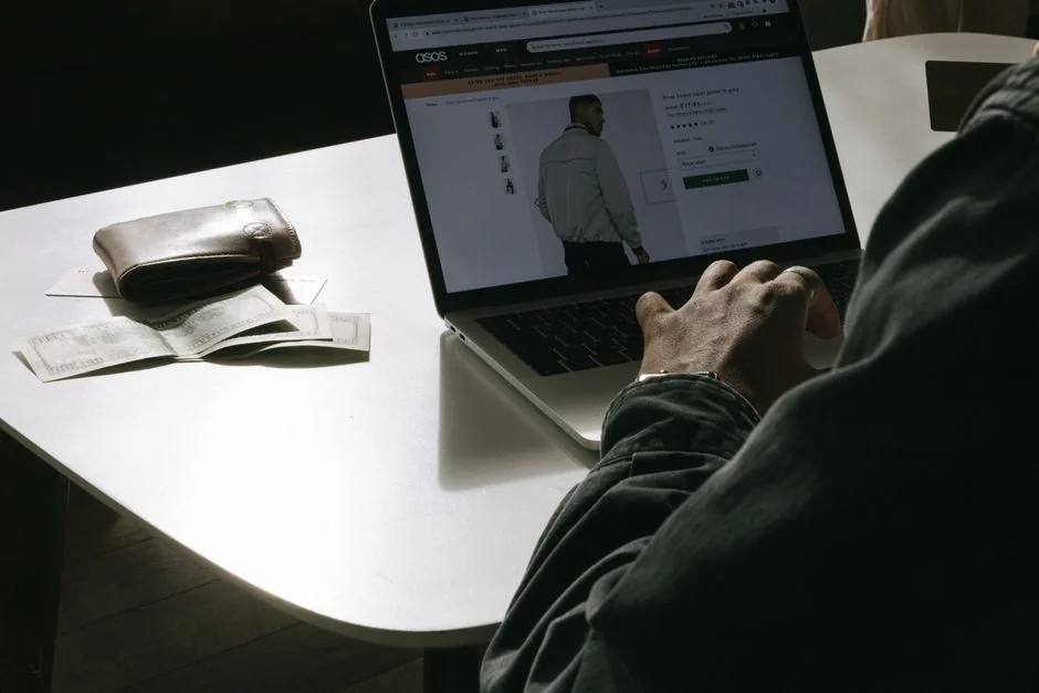 Man editing photos on a laptop using a graphics tablet, set in an indoor workspace with camera equipment.